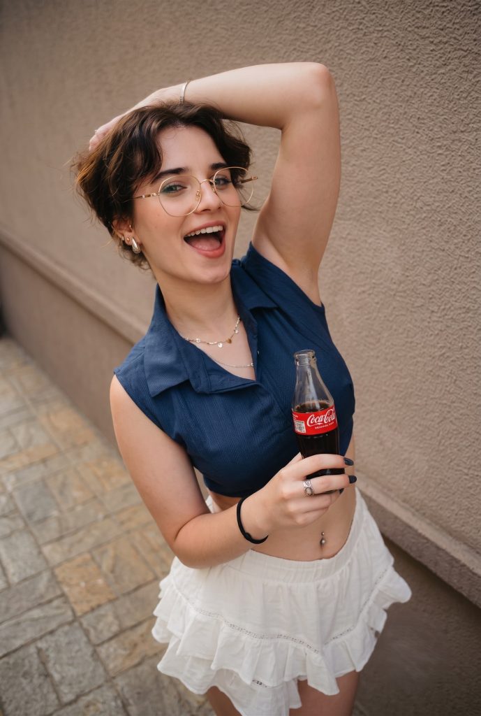 A smiling woman holding a glass bottle of Coca-Cola.
